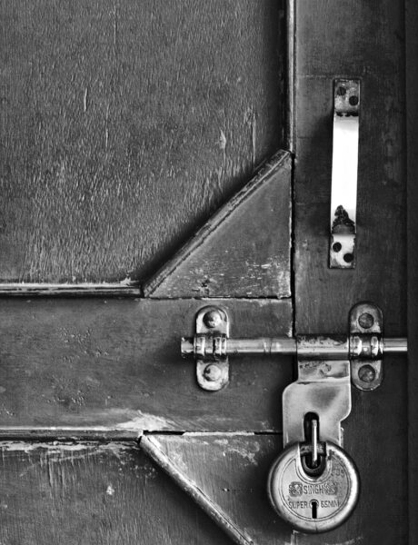 Padlocked wooden door secured with a metal bolt